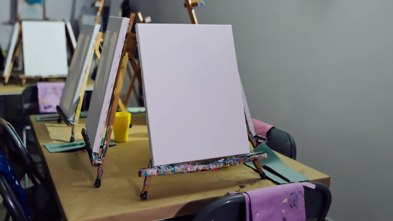 艺术家的工作场所，画架上的白色帆布和艺术学校教室里的椅子特写。学院设备视频下载