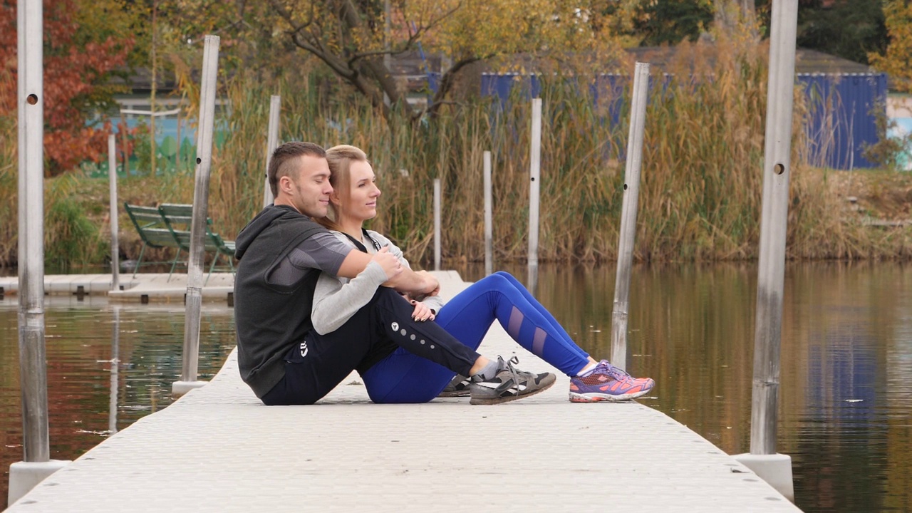 早晨，一对年轻情侣在湖边坐着拥抱视频下载