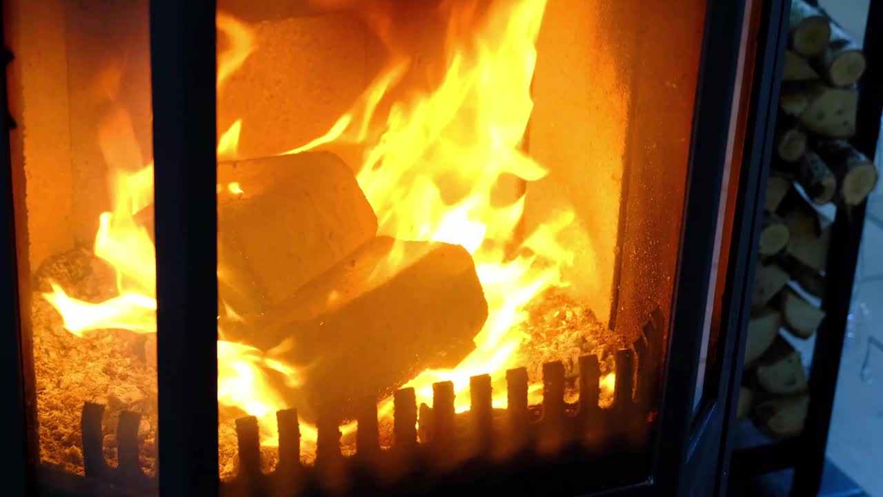 由压制木屑制成的燃料煤球，用于点燃炉子-经济的替代环保燃料，用于室内壁炉。屋里的炉子里正在烧木柴视频素材