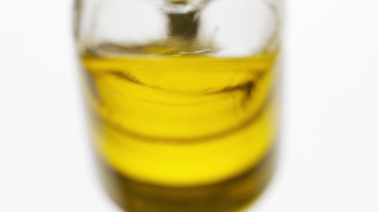 试剂瓶倾斜，葵花籽油从瓶子里倾泻而出视频素材