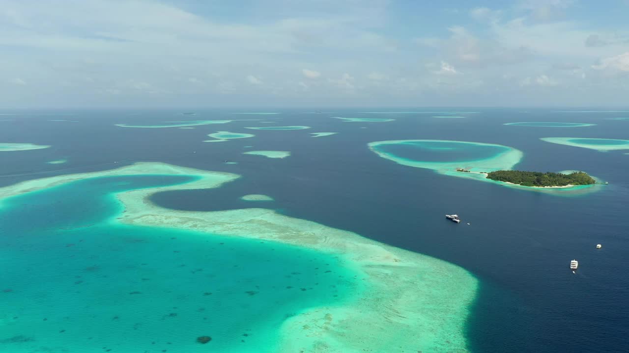 空中拍摄的环礁在阳光明媚的日子里，无人机与船只飞越海洋- thulushoo，马尔代夫视频素材
