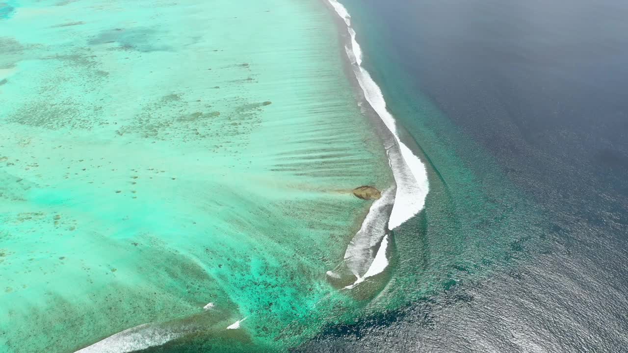 航拍海浪飞溅附近环礁在阳光灿烂的一天，无人机飞越海洋- thulushoo，马尔代夫视频素材