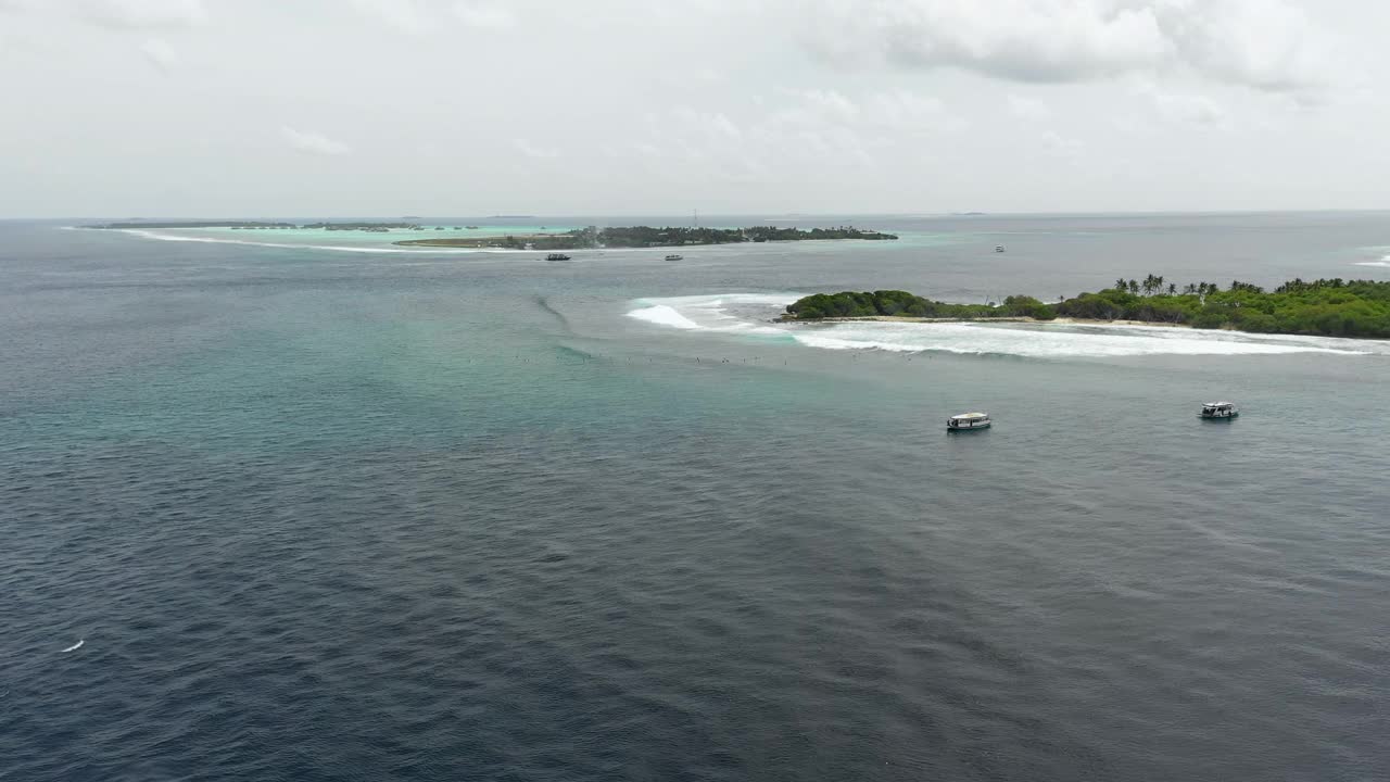 空中平移拍摄的船只在海上附近的岛屿对天空，无人机飞过海浪飞溅在海洋- thulushoo，马尔代夫视频素材
