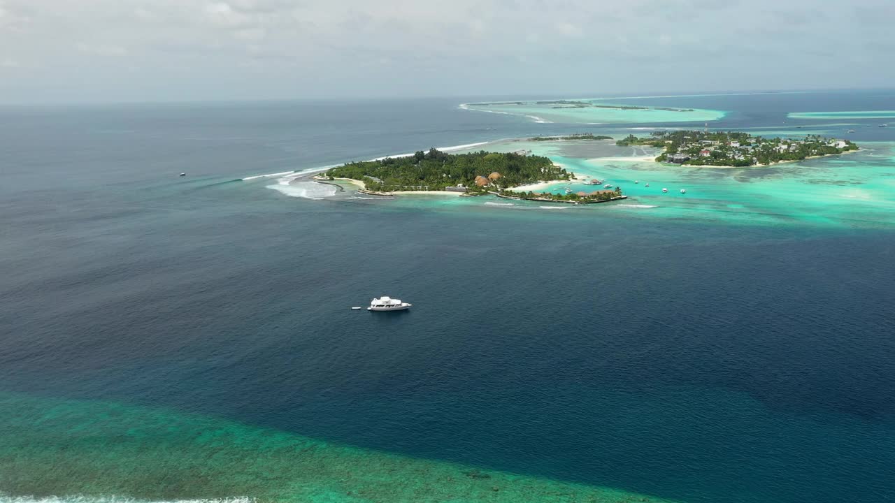 在多云的天空中，海上岛屿附近的船只航拍镜头，无人机在阳光明媚的日子飞越海洋- thulushoo，马尔代夫视频素材