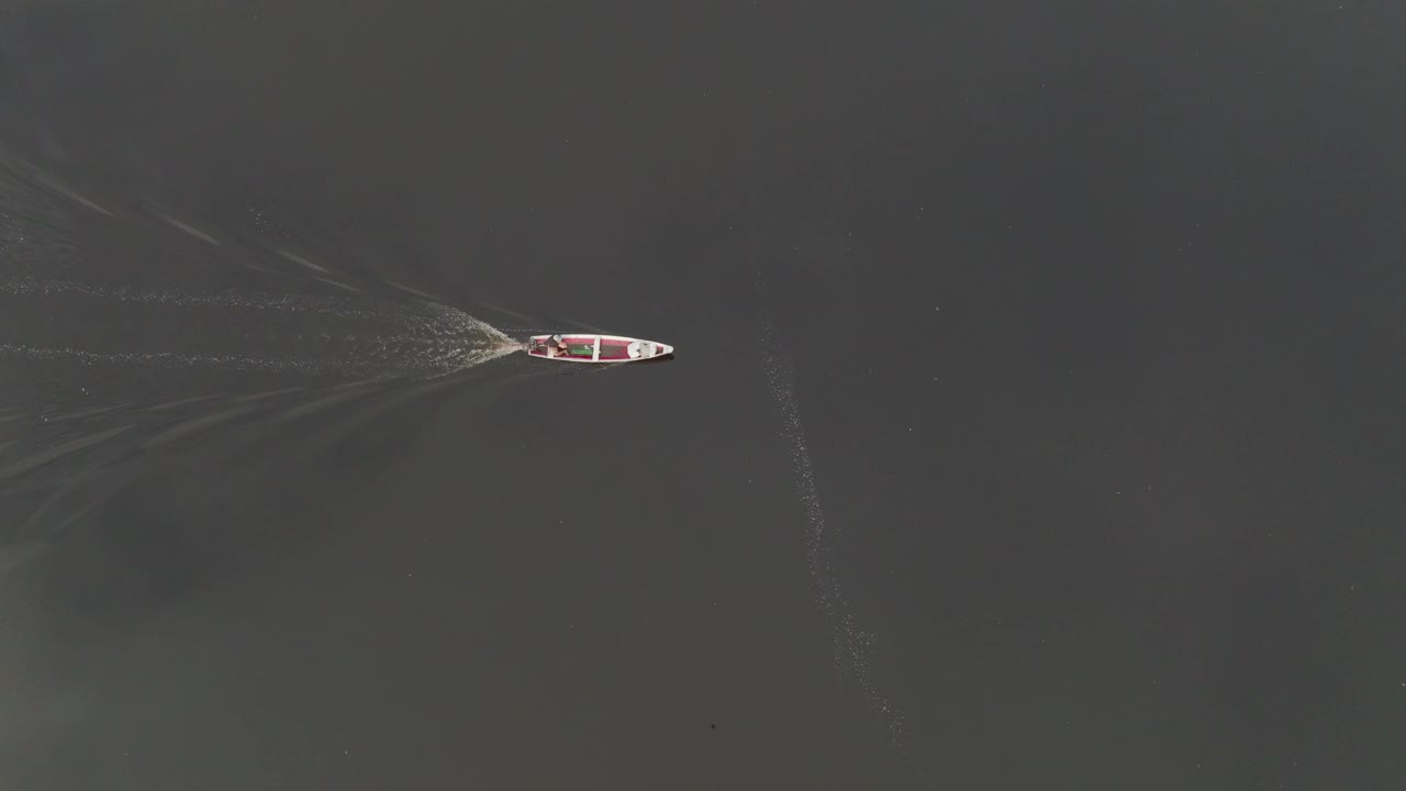 航拍的顶部平移拍摄的人在船上移动在荡漾的河流在度假期间探索-马瑙斯，巴西视频下载