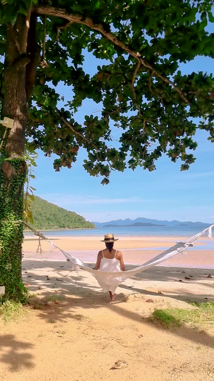 度假期间，一对男女躺在泰国麦岛海滩上的吊床上视频素材