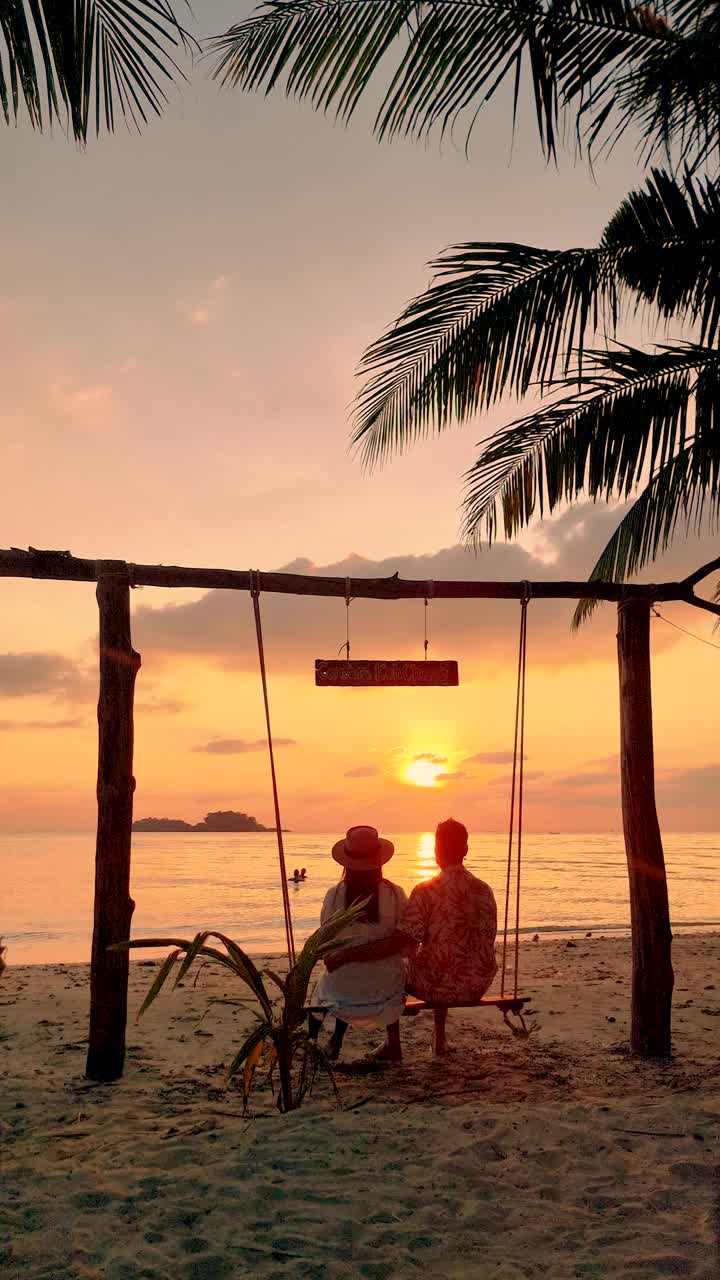 日落时分，一对男女在泰国长岛的海滩上荡秋千视频素材