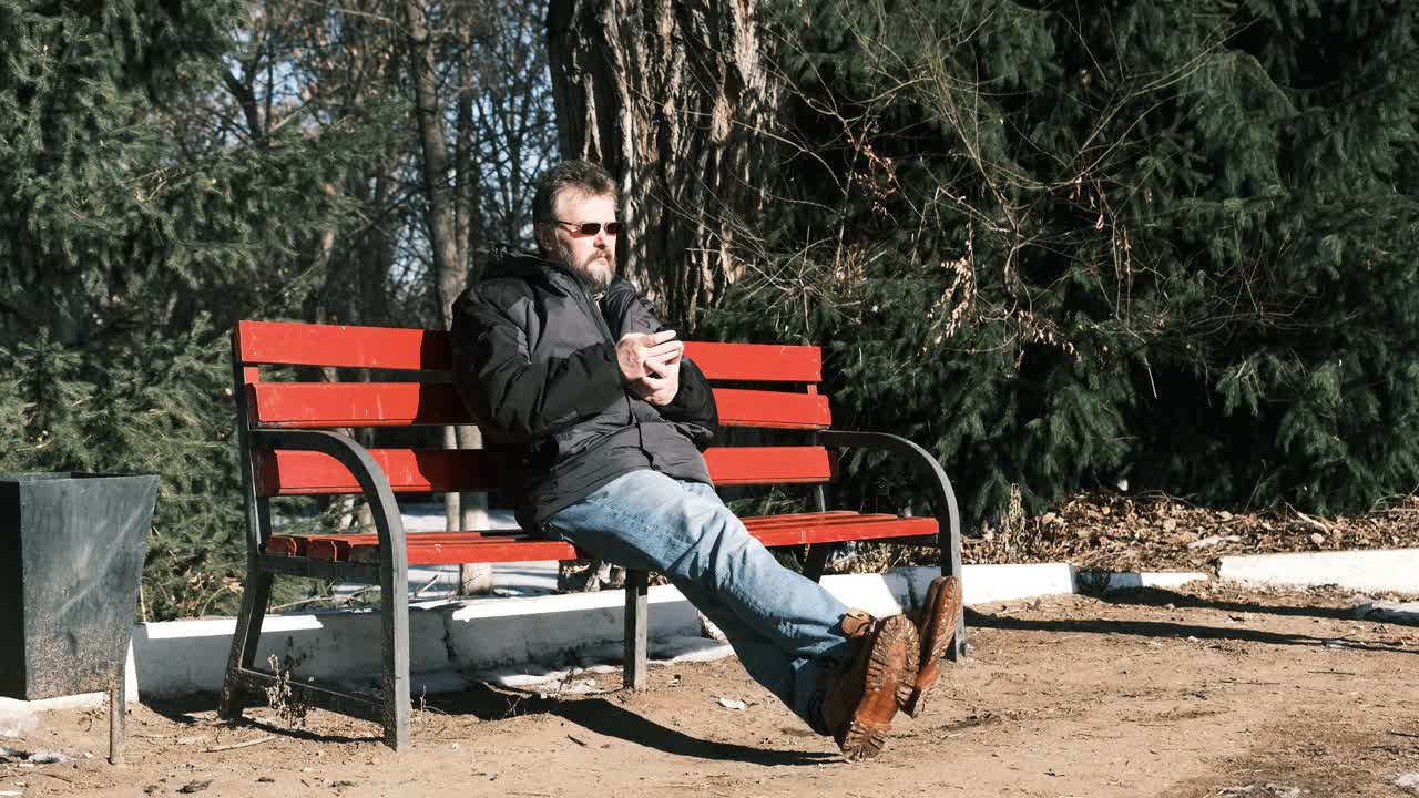 成熟的男人坐在公园的长椅上看着路过的女人视频下载