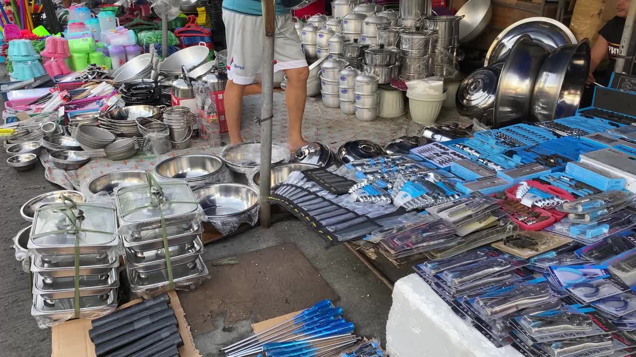 在城镇节日期间，家庭用具、厨具和工具被沿街的边缘小贩摆放在路边，展示和出售。视频下载