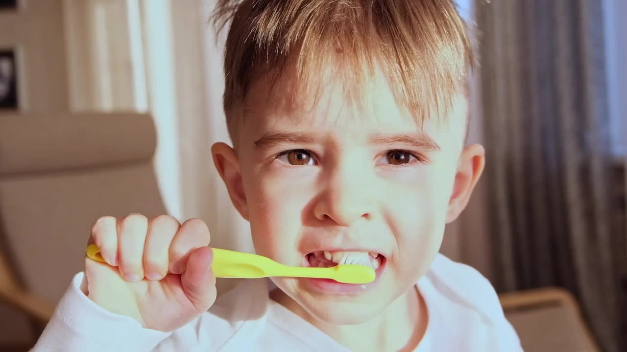 金发男孩学步3岁饭后在房间勤奋地用牙刷刷牙。健康的习惯。特写FHD慢镜头视频下载