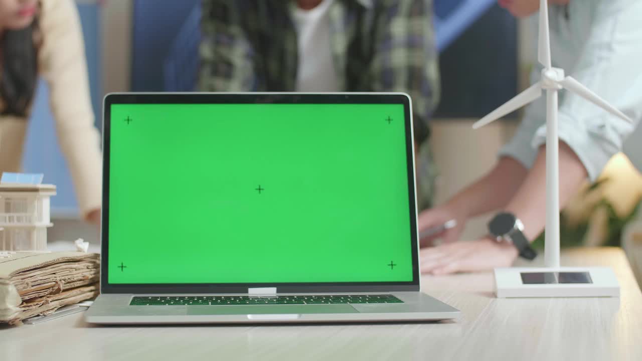 当工程师们在办公室讨论蓝图工作时，桌子上的绿色屏幕笔记本电脑的特写视频下载