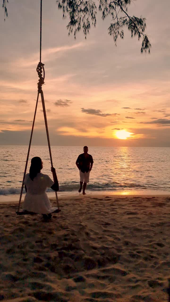 一对男女在泰国Koh Kood海滩上的秋千上日落时分视频素材