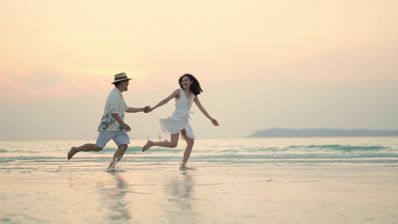 4K快乐的亚洲情侣在夏日夕阳下一起在沙滩上玩耍视频素材