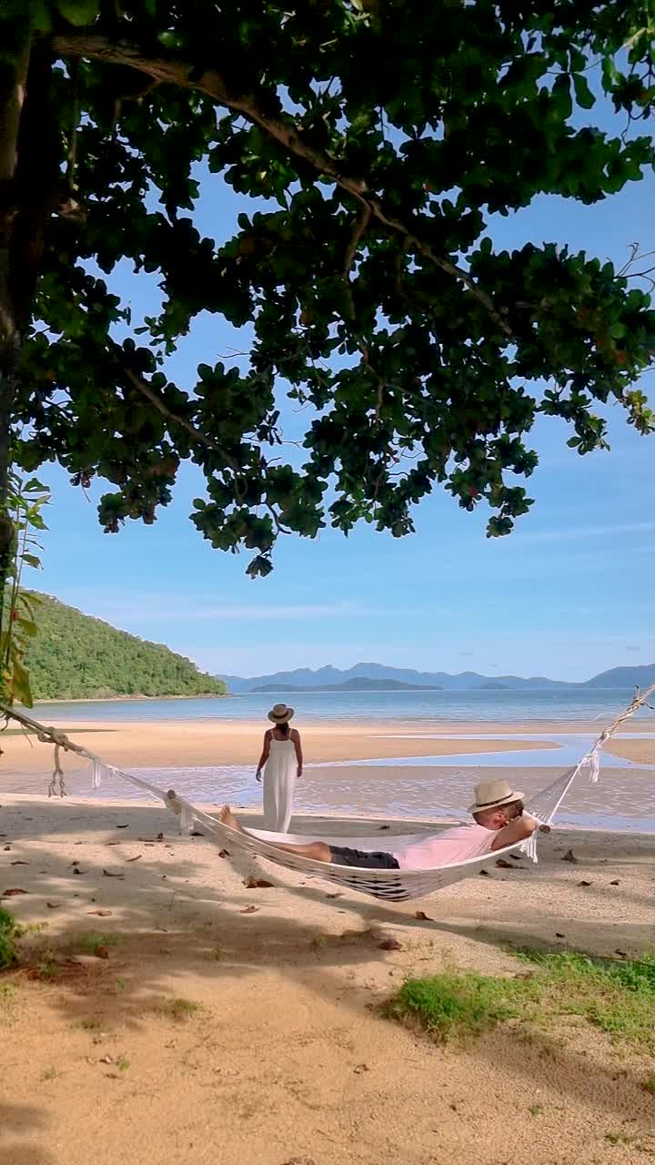 早晨，一对男女躺在泰国麦岛海滩上的吊床上视频素材