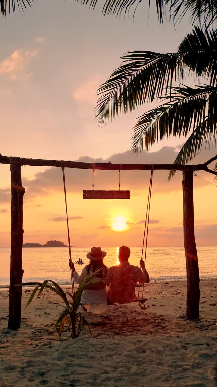 日落时分，一对男女在泰国长岛的海滩上荡秋千视频素材