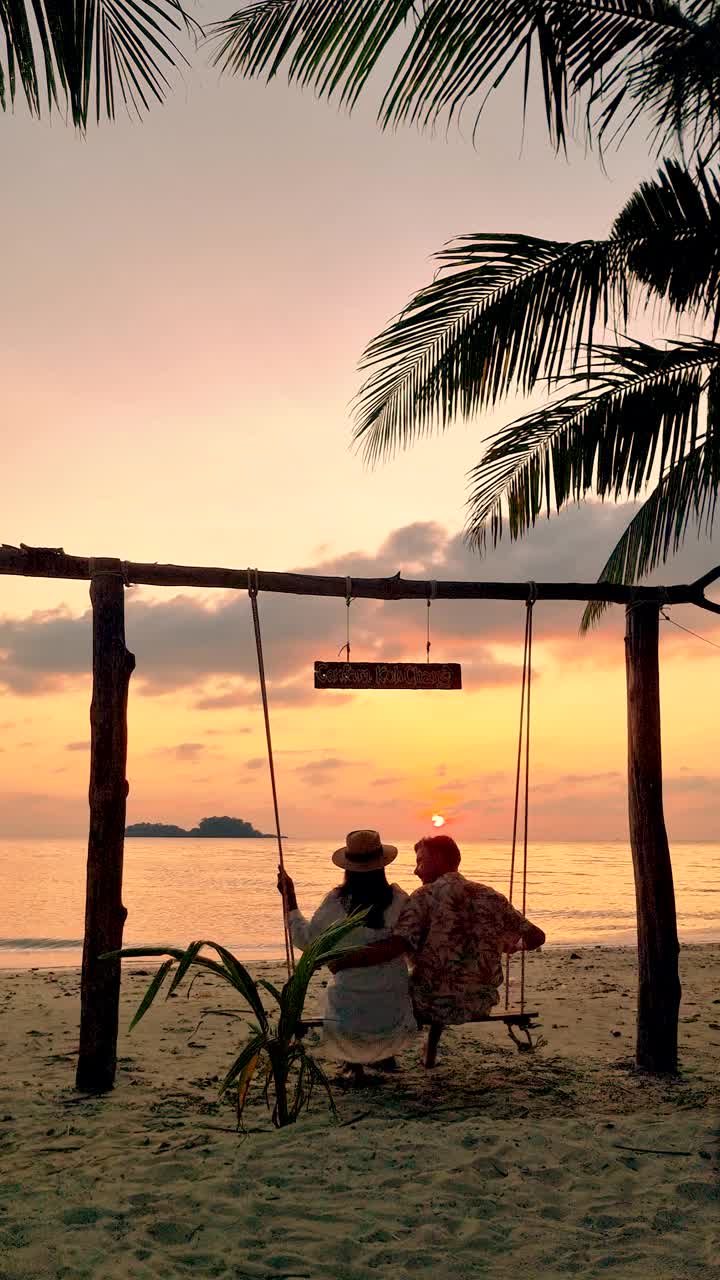日落时分，一对男女在泰国长岛的海滩上荡秋千视频下载
