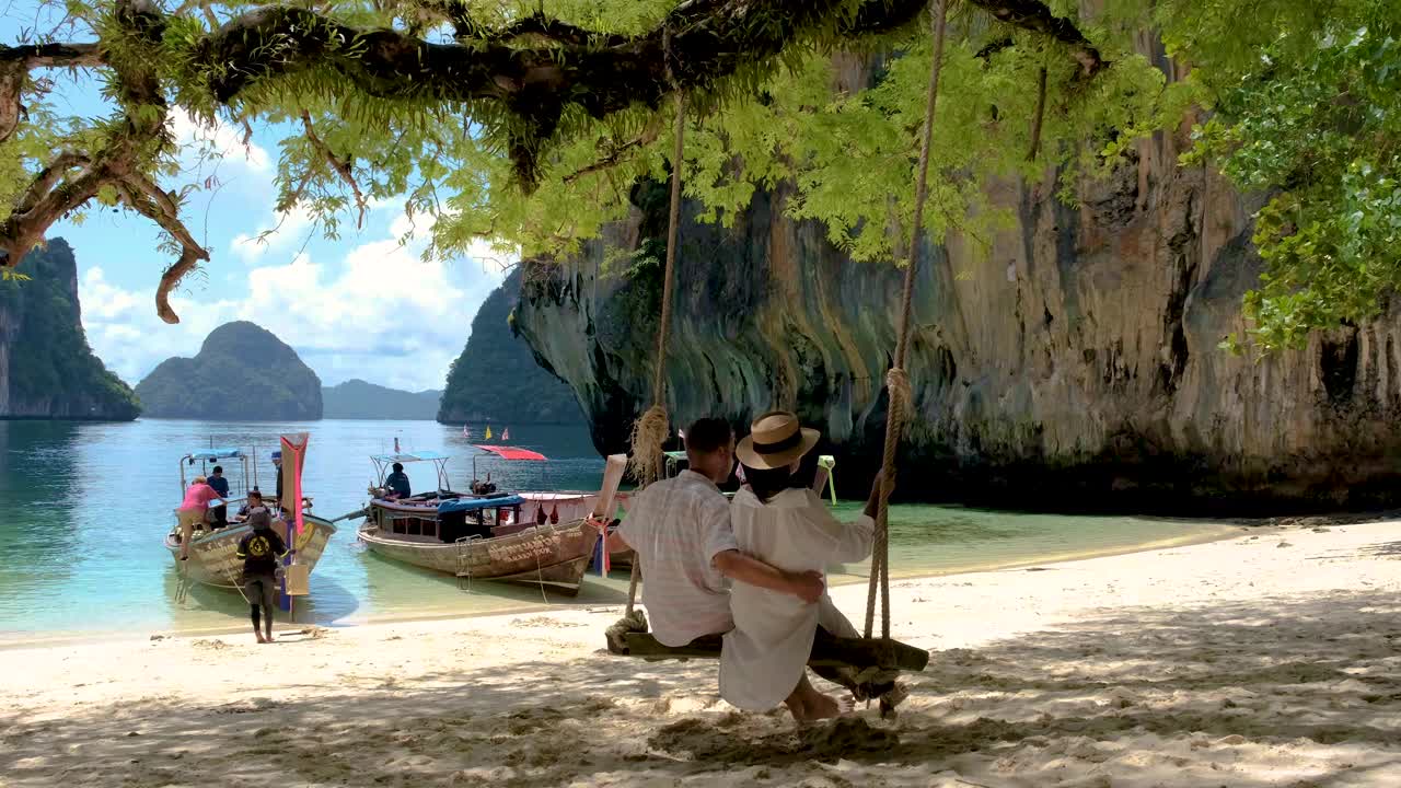 一对男女在泰国老腊岛的热带白色沙滩上荡秋千视频素材