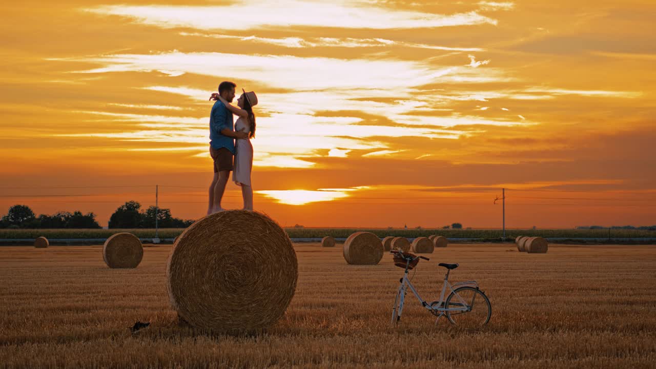 手持慢动作镜头，中年夫妇站在田间的干草堆上拥抱亲吻视频素材