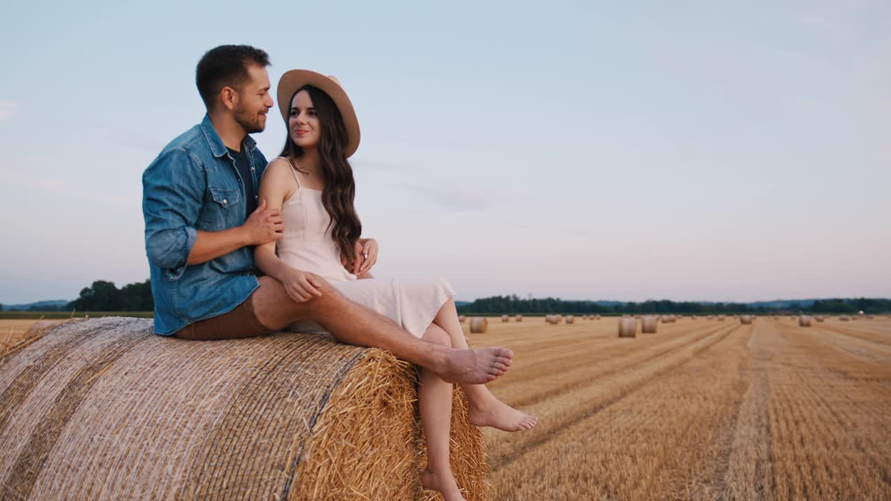 手持慢动作镜头，中年夫妇坐在干草堆上，拥抱，享受日落视频素材