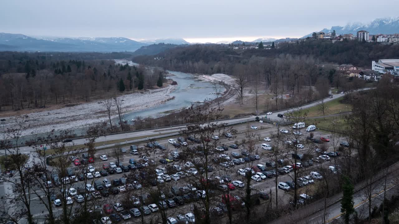 时间从白天到夜晚，高空鸟瞰城市的汽车停在山间的河上视频下载