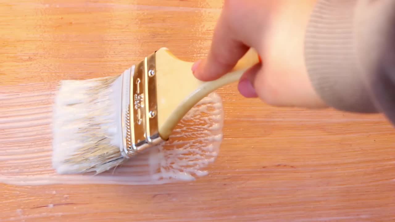 在家中进行室内装修时，用白色丙烯酸清漆在木板上刷漆视频素材