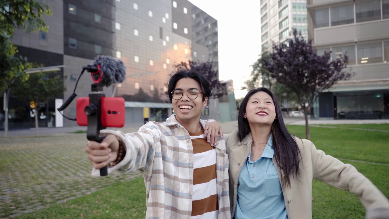 年轻的亚洲夫妇微笑着拿着相机在泰国曼谷拍摄视频和照片，在东南亚旅行视频下载