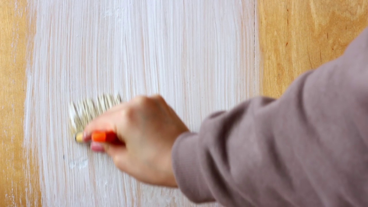 在家中进行室内装修时，用白色丙烯酸漆将木板涂上油漆视频素材