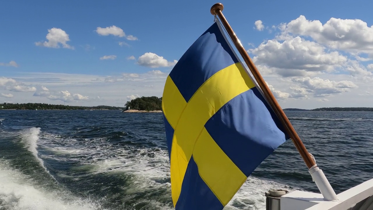 瑞典国旗在斯德哥尔摩群岛航行的船只尾部飘扬。右边旗帜的特写视频视频下载