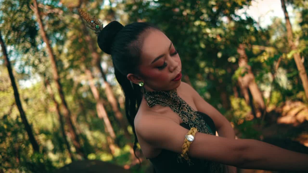 巴厘岛女人穿着绿色的衣服，化着绿色的妆，在森林里跳舞视频素材