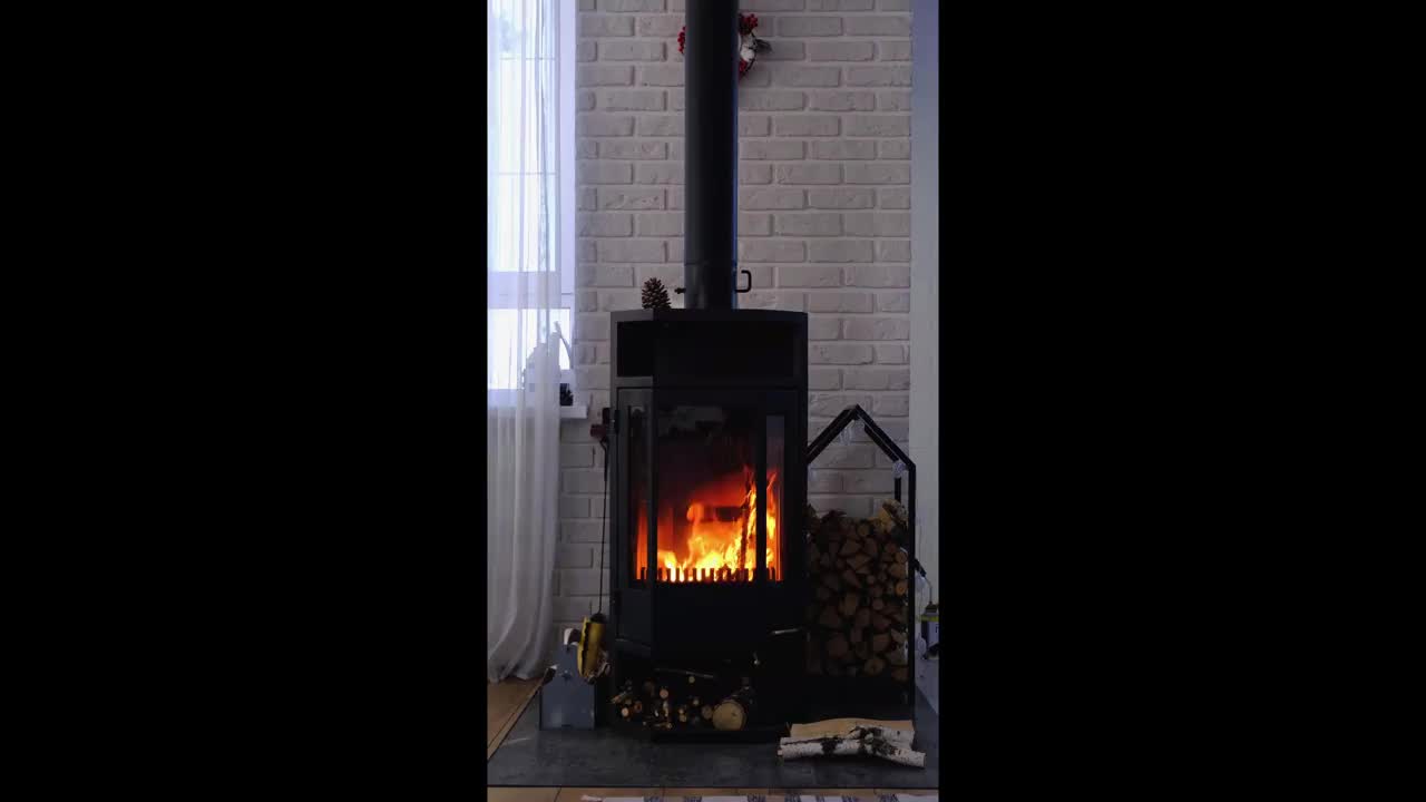 黑色火炉，阁楼风格的房子内部的壁炉。替代环保供暖，温暖舒适的房间在家里，燃烧木材。垂直视频视频素材