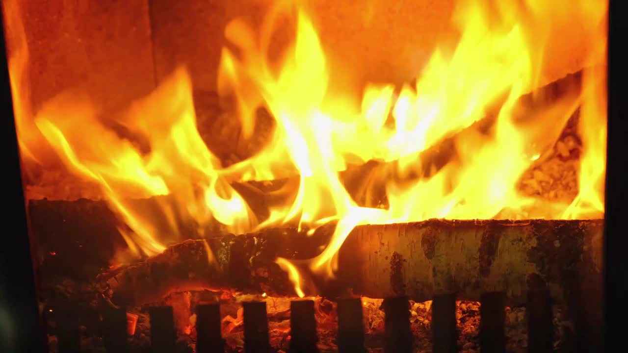 特写镜头下，柴火正在炉膛里燃烧。替代环保供暖，温暖舒适的房间在家里，燃烧木材视频素材