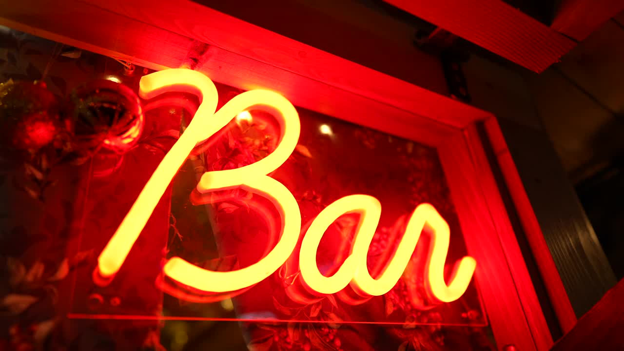 酒吧的荧光灯标志在夜间流动的大门。红条广告业务在黑暗中发光视频下载