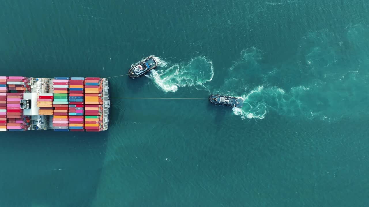 拖船拖着大货集装箱船。远洋集装箱船与拖船的船尾。货船由拖船拖曳视频下载