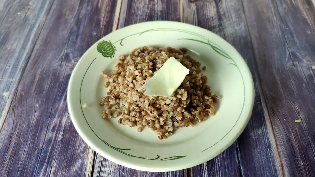 白盘子里盛着煮好的荞麦，木桌上放着黄油视频下载