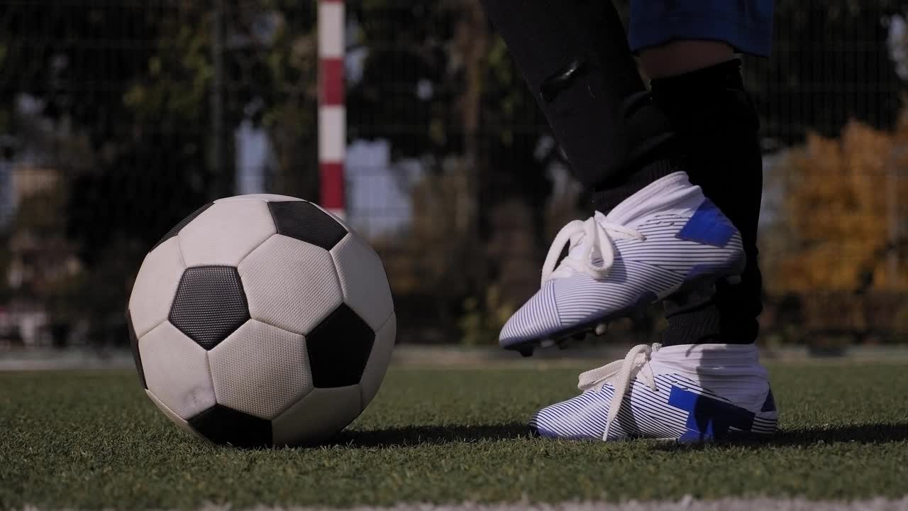 一个足球的特写，一个小男孩把他的脚放在足球上。视频下载