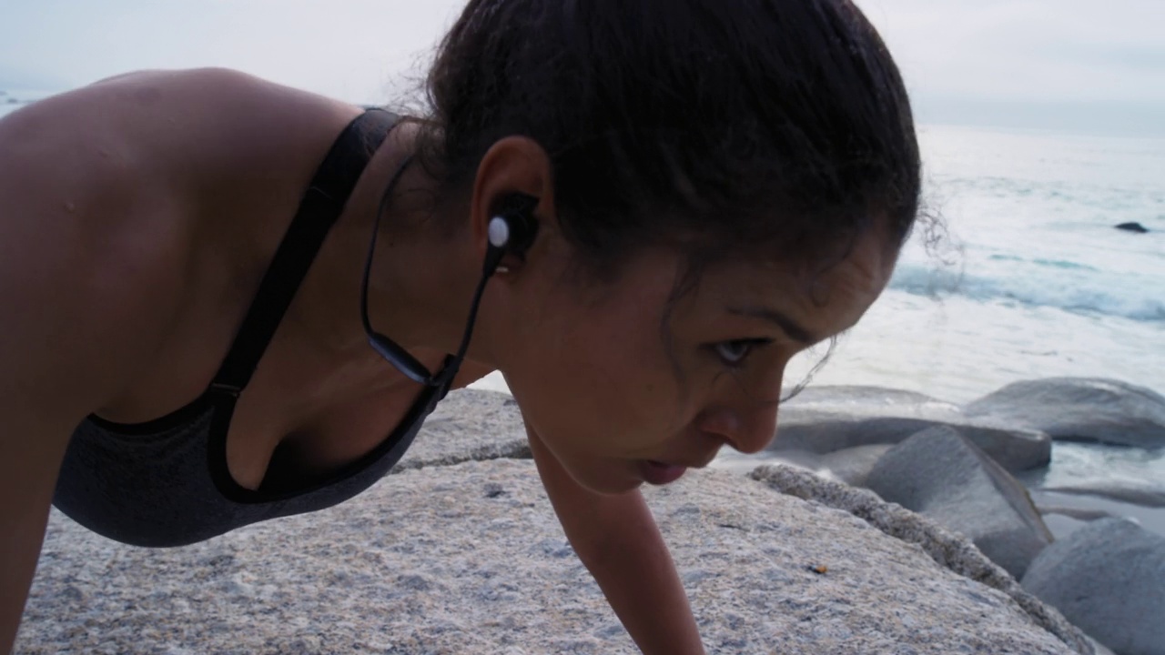 女性，耳机或在日落健身的海滩上进行俯卧撑锻炼，训练或锻炼身体肌肉增长，保健健康或目标。体育运动员，私人教练或自然俯卧撑音乐视频下载