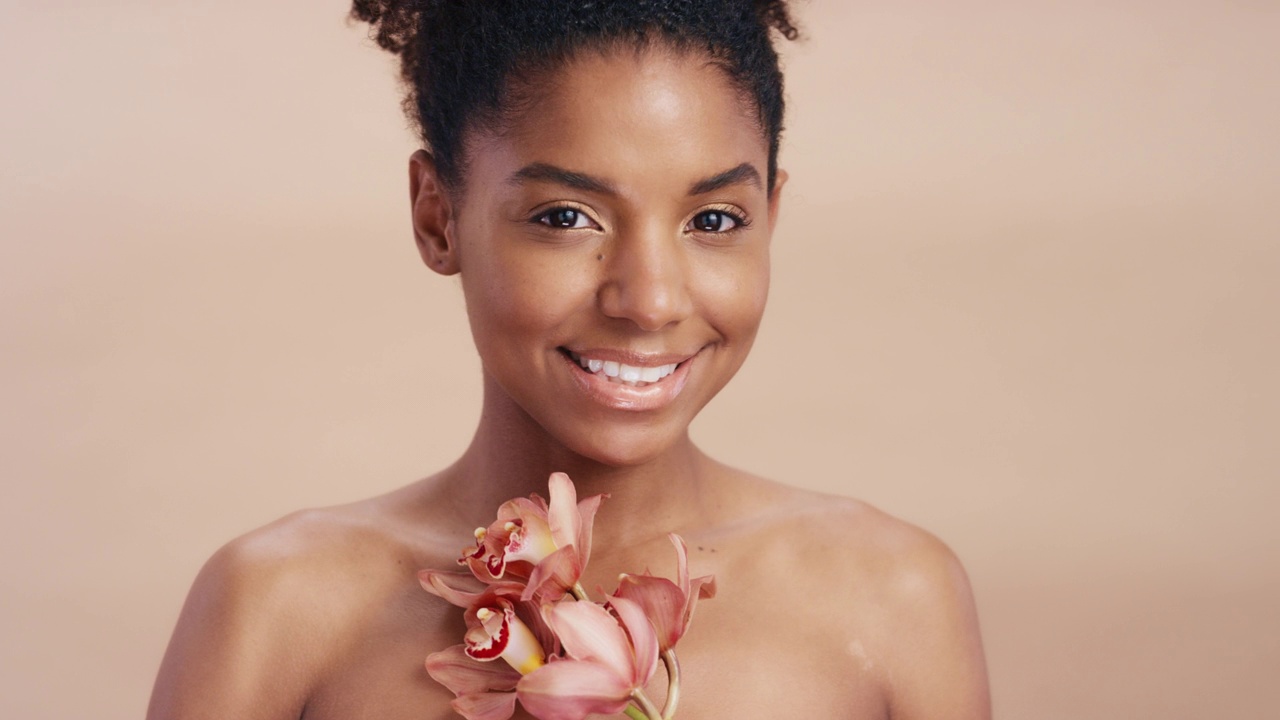 黑人女性，脸和花在美容护肤，卫生或自然治疗对工作室的背景。肖像微笑的非裔美国女模特抱着植物在有机护理完美的皮肤视频下载
