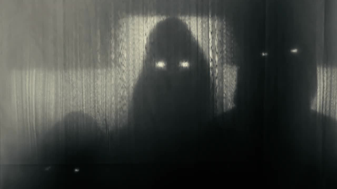 三个戴着兜帽的人的剪影，在透明的窗帘后面，眼睛闪闪发光，抬起头，伸出手。恶魔，超自然现象，鬼魂的概念。4k视频60帧。视频下载