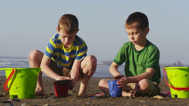 两个男孩在沙滩上玩沙子视频素材