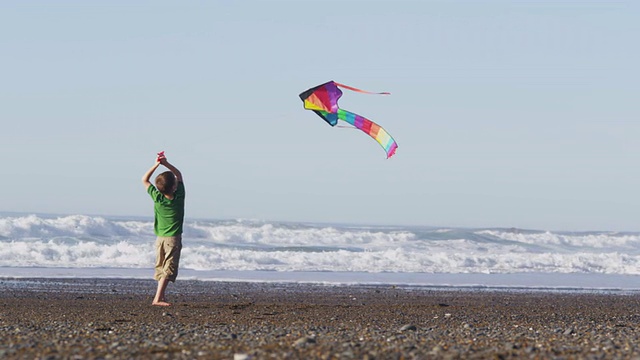 小男孩在海滩放风筝，慢镜头视频素材