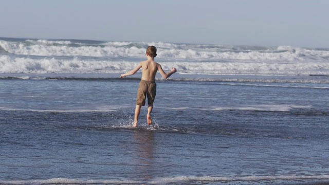小男孩在海浪中奔跑，慢镜头视频素材