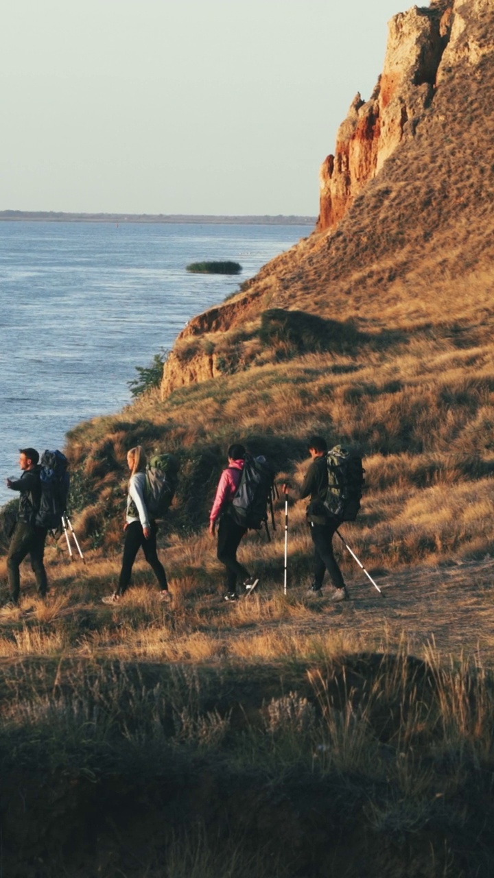 四个人背着背包走在海边的山坡上视频下载