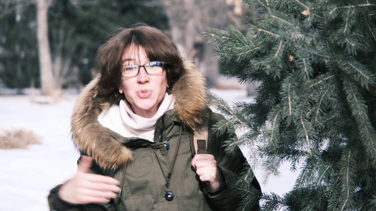 冬季公园里，一个成熟的女人正从树后往外看视频下载