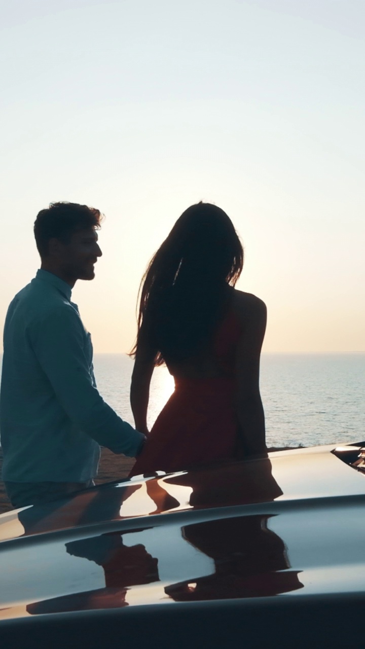 海边，一对浪漫的情侣站在汽车旁。慢动作视频下载