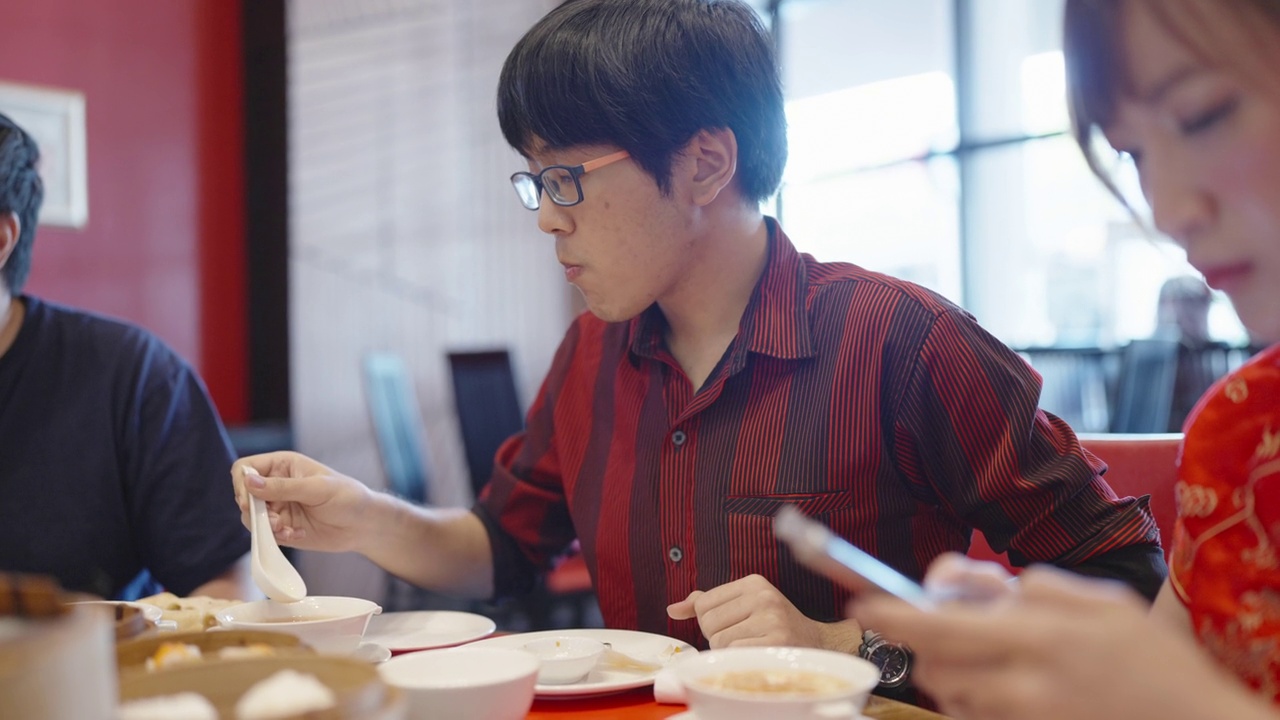一名亚洲男子在中国餐馆的派对上喝汤和饺子视频下载