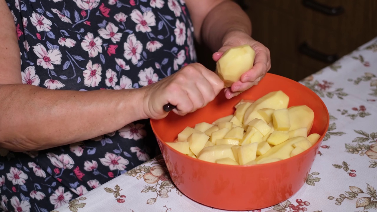 女性在家里的厨房里切新鲜的生土豆视频素材