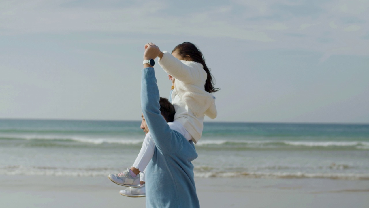 快乐的父亲和可爱的小女儿在海边玩耍视频下载