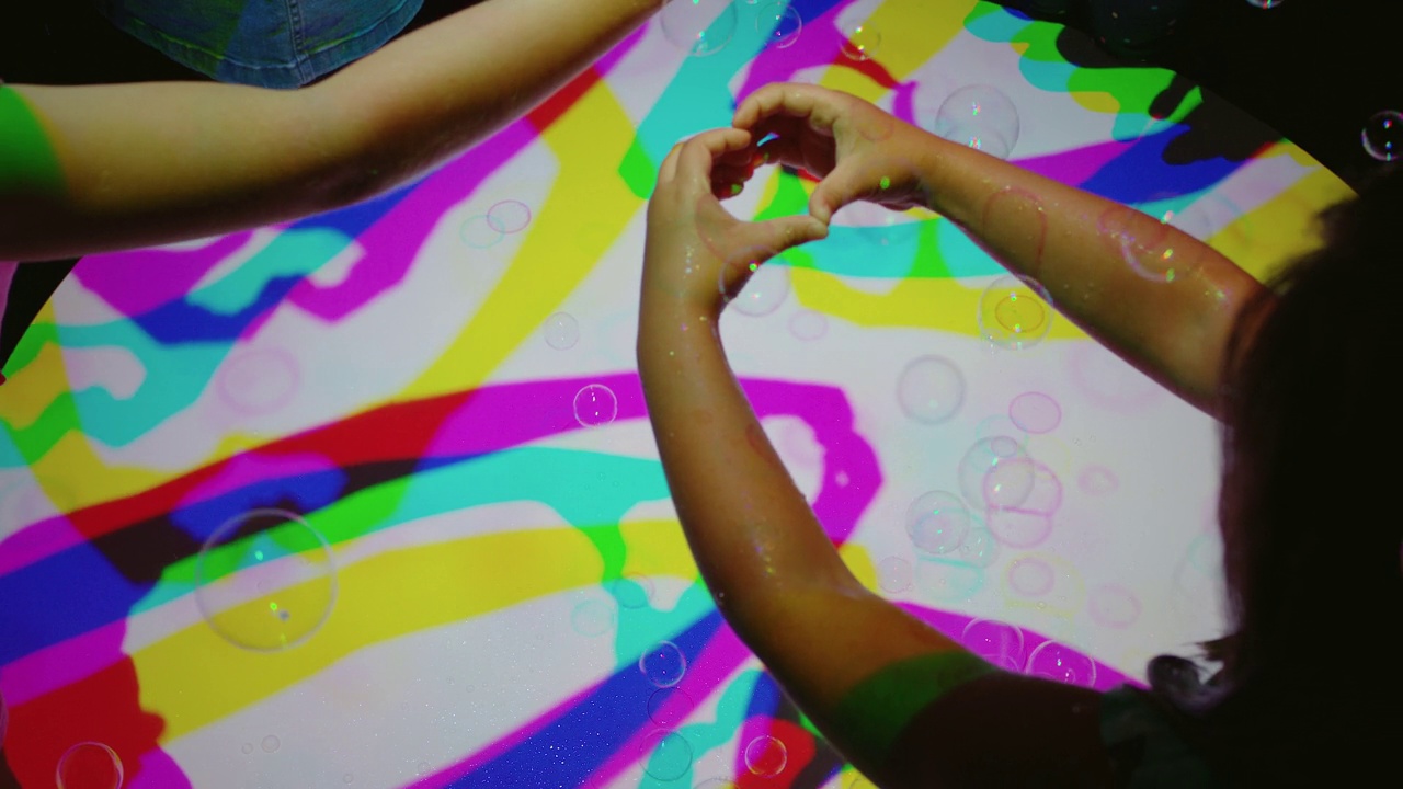 五彩缤纷的手制作心形的孩子们玩得很开心，在五彩缤纷的灯光下，孩子们玩起了彩虹色彩的游戏视频素材