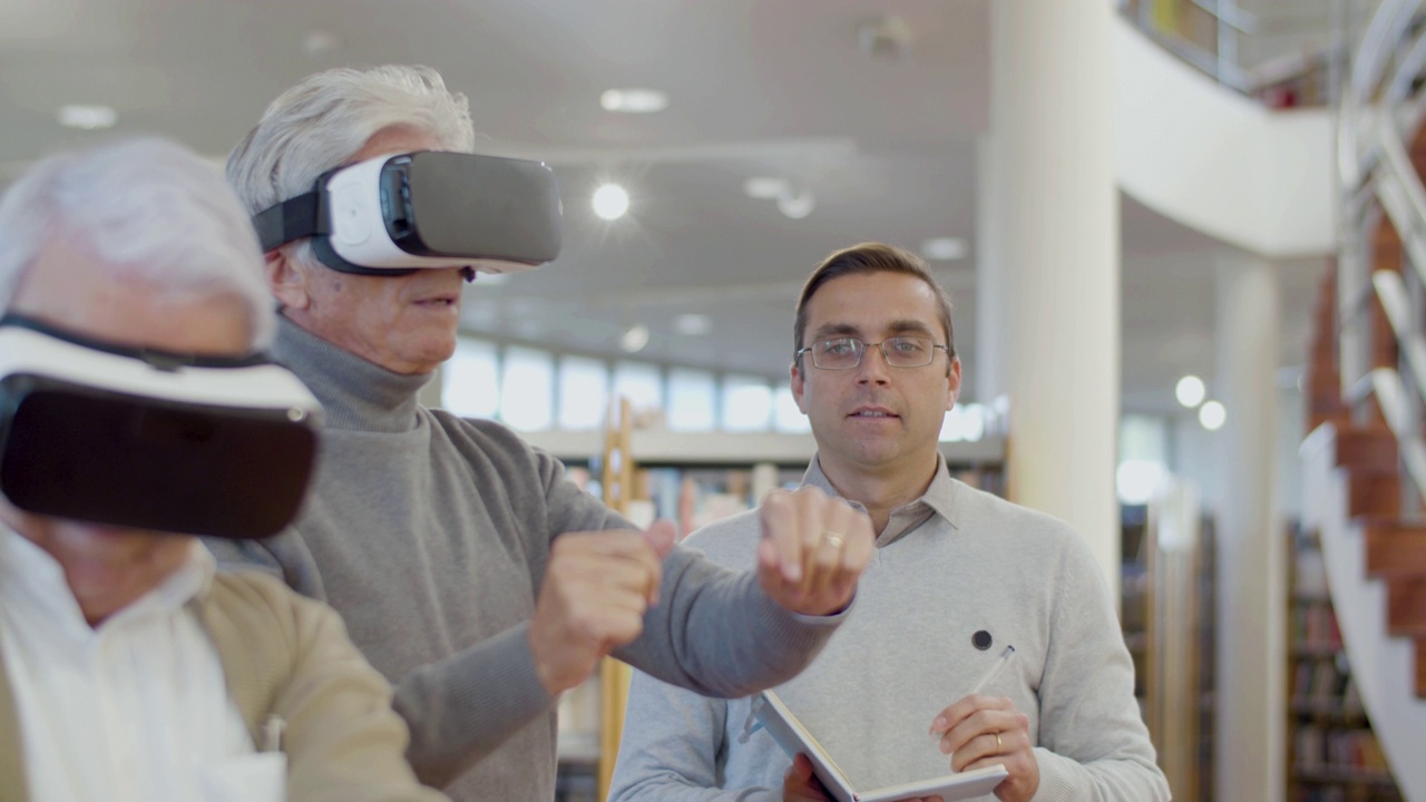 老年人带着VR眼镜和老师在图书馆视频下载