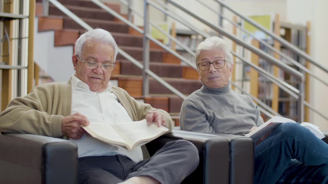 年长的白人男人坐在图书馆里聊天视频下载